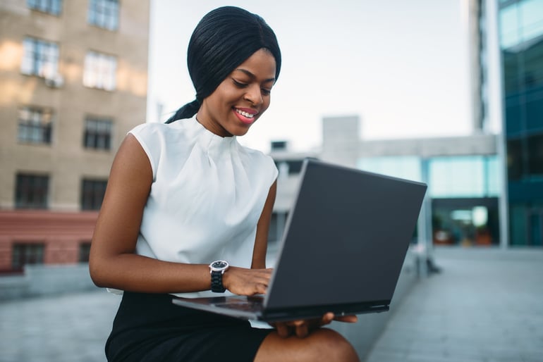 business-woman-uses-laptop-against-office-TUWGLHR-min