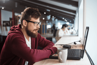  young-man-in-glasses-sitting-and-using-laptop-PS5DZEH 