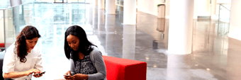  two-businesswomen-using-mobile-phones-in-lobby-of-P95QCDL-1 
