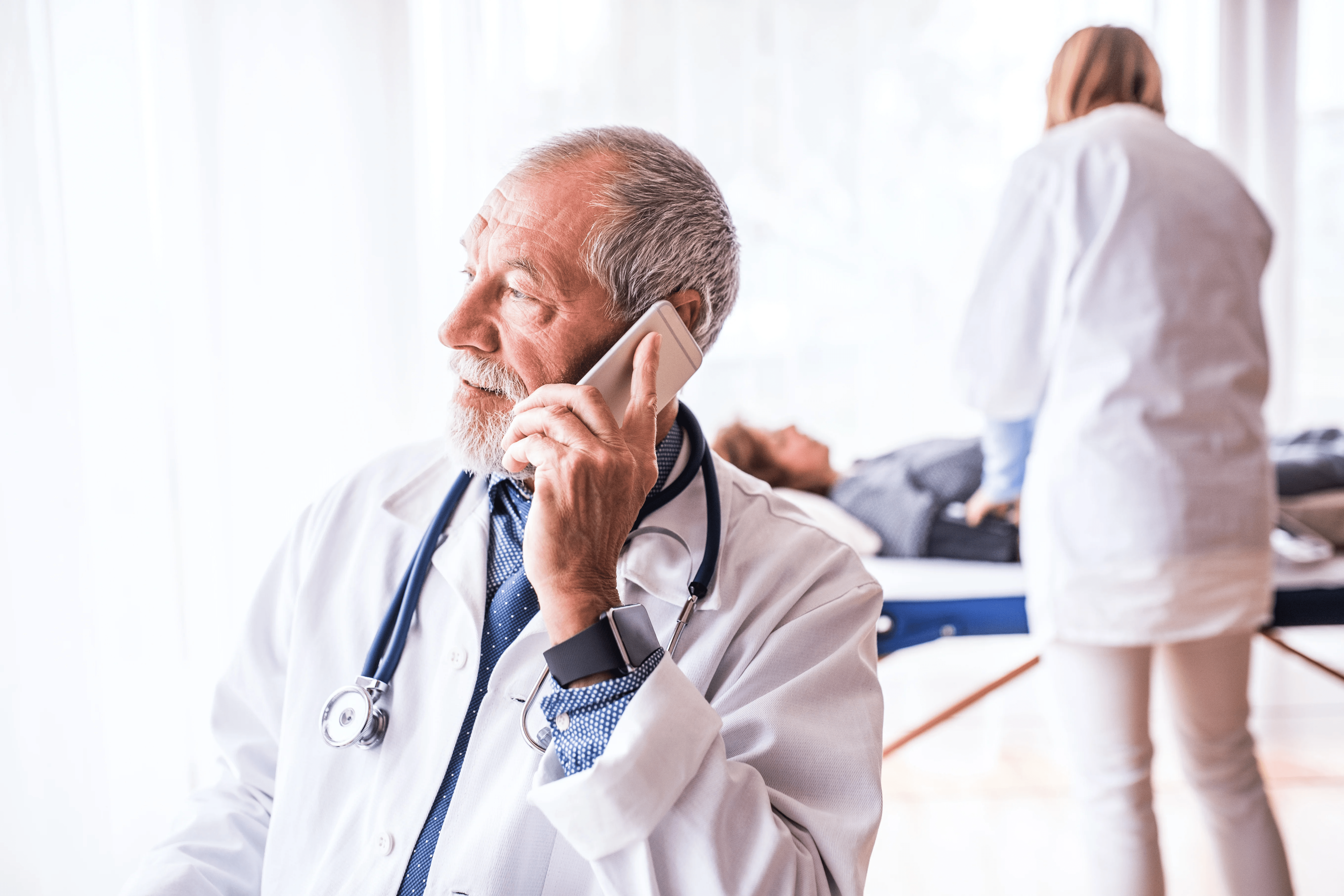 senior-doctor-with-smartphone-in-his-office-P3A8S6Z